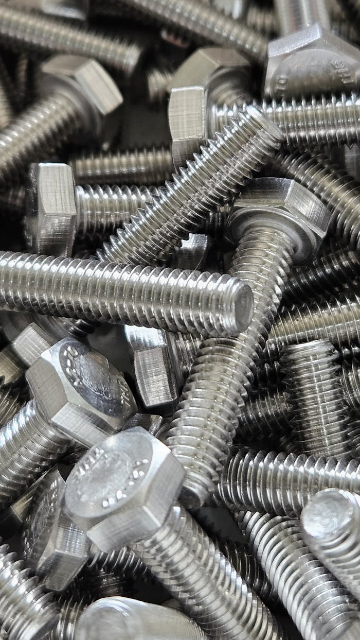 Detailed image of numerous shiny steel hex bolts, ideal for industrial use.